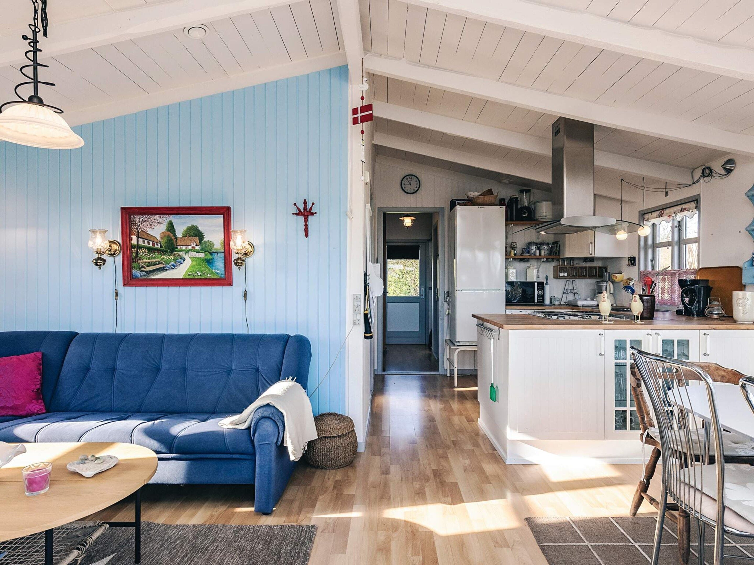 Ein Wohnzimmer mit einem blauen Sofa, einem Holztisch und einem Gemälde an der Wand.