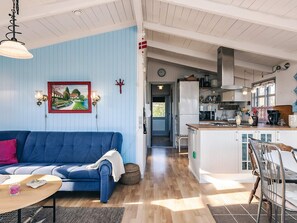 A living room with a blue sofa, a wooden coffee table, and a painting on the wall. - 4 Person Holiday Home in Snedsted (Snedsted)