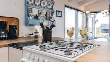 Una cocina con estufa a gas, cafetera y objetos decorativos en estanterías.