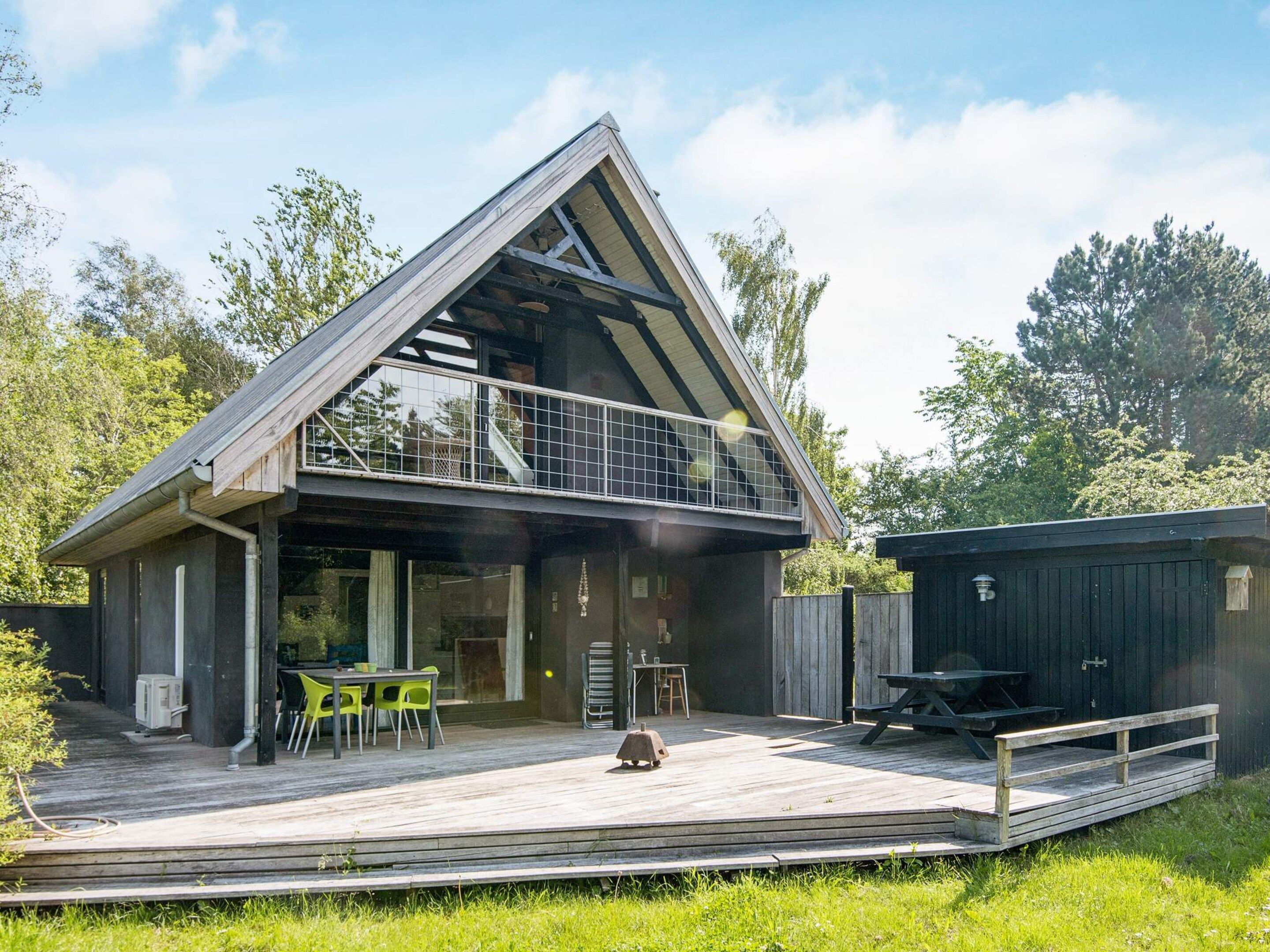 Une maison moderne dotée d’une terrasse en bois, d’un coin repas avec des chaises et d’une petite table d’extérieur.