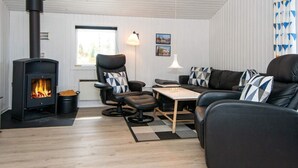 A cozy living room with a black sofa, a black leather chair, a small table, and a black wood-burning stove.