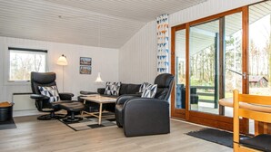 A modern living room with a sofa, chairs, a table, and a large window.