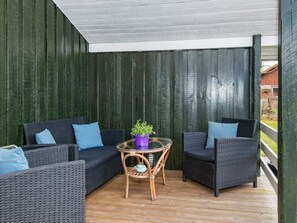 A covered outdoor seating area with wicker furniture and a glass table.