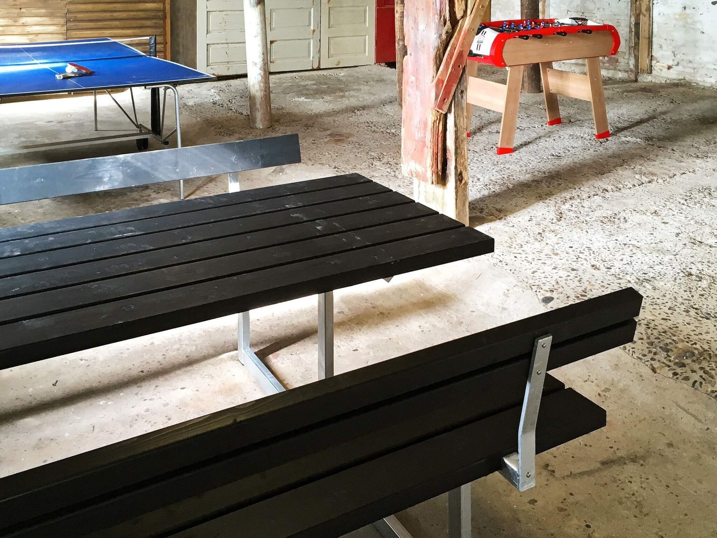 A table and bench in a room with a concrete floor and wooden walls.