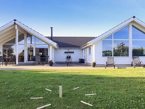 A two-story house with a covered patio, a chimney, and a large window. - 5 Star Holiday Home in Stege (Stege)