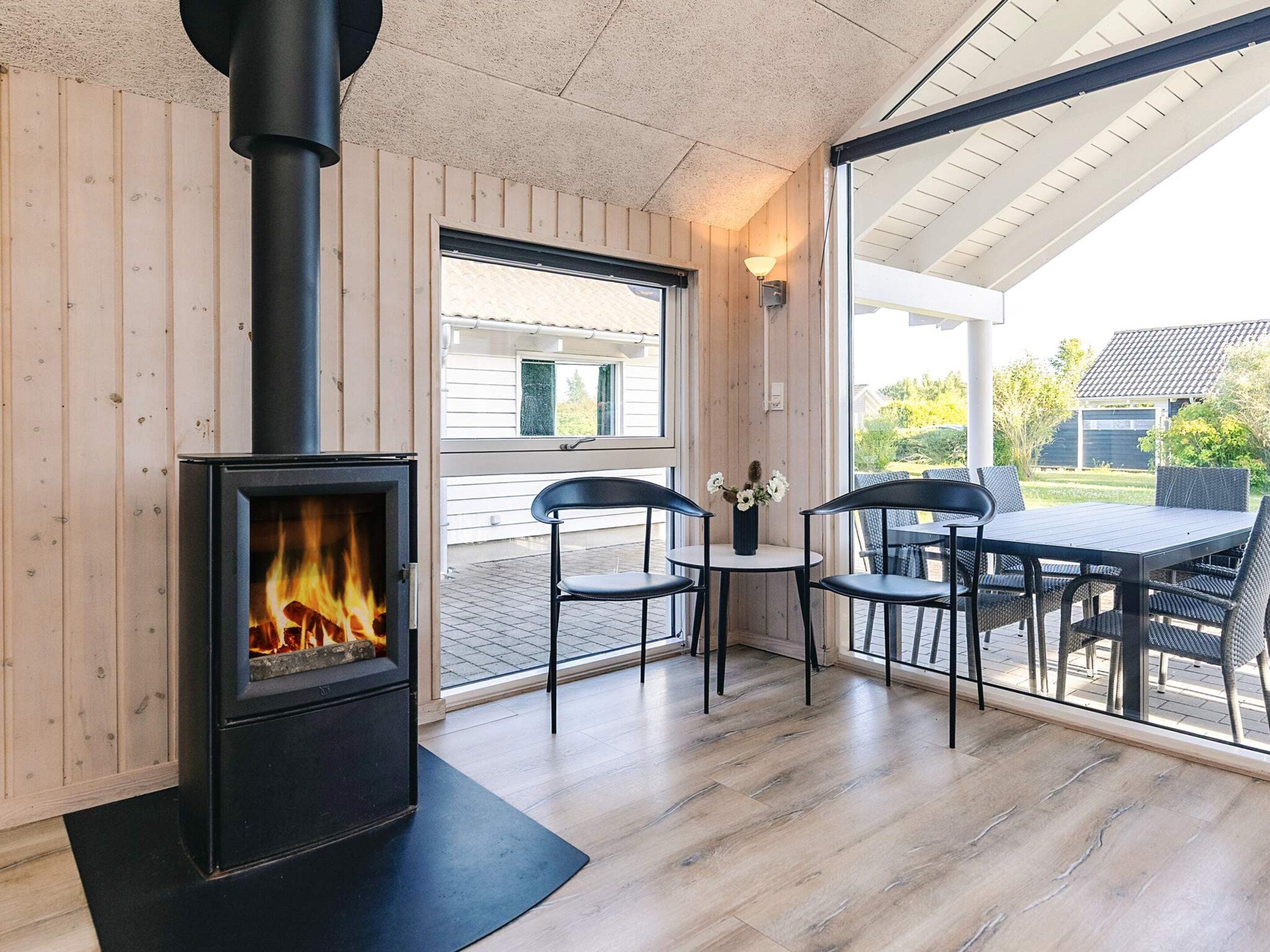 Une pièce avec un poêle à bois, une table à manger avec des chaises et une vue à travers une porte vitrée.