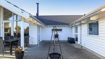 A patio with a grill, a ladder, and a potted plant.