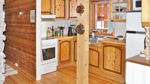 A kitchen with wooden cabinets, a stove, a sink, and a microwave. - 11 Person Holiday Home in Edland (Vinje)