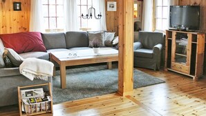A wooden-paneled room with a sofa, armchair, TV stand, and a small table. - 11 Person Holiday Home in Edland (Vinje)