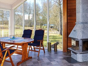 A cozy indoor space with a round wooden table, two blue chairs, and a stone fireplace. - Holiday Home in Kalv (Kalv)