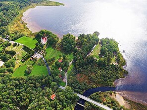 An aerial view of a coastal property with a large house, a bridge, and a beach. - Holiday Home in Kalv (Kalv)