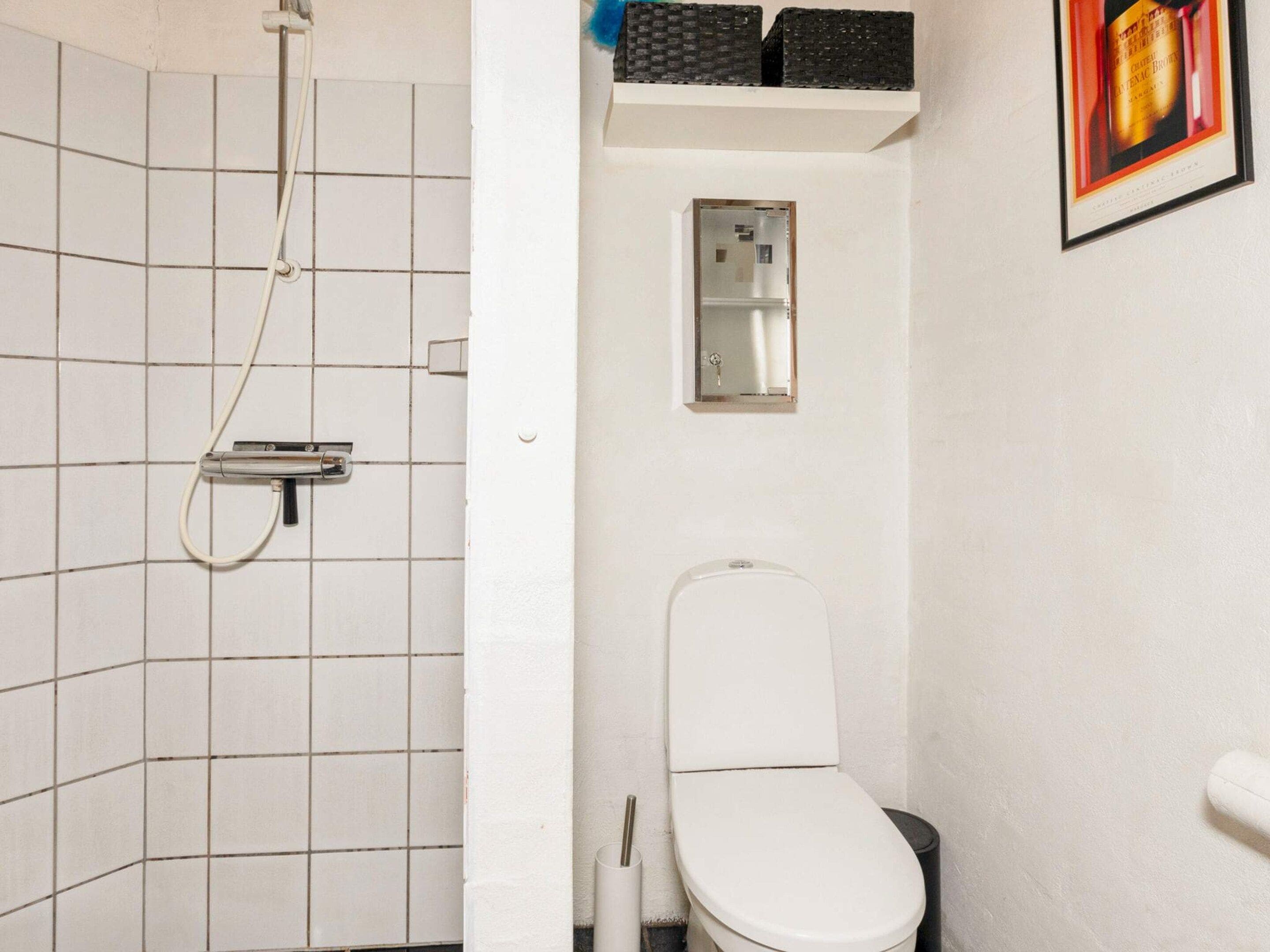 Um banheiro pequeno com azulejos, chuveiro, vaso sanitário e um espelho.