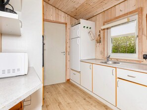 A compact kitchen with a refrigerator, a microwave, and a window with a view of greenery. - 5 Star Holiday Home in Vestervig (Vestervig)