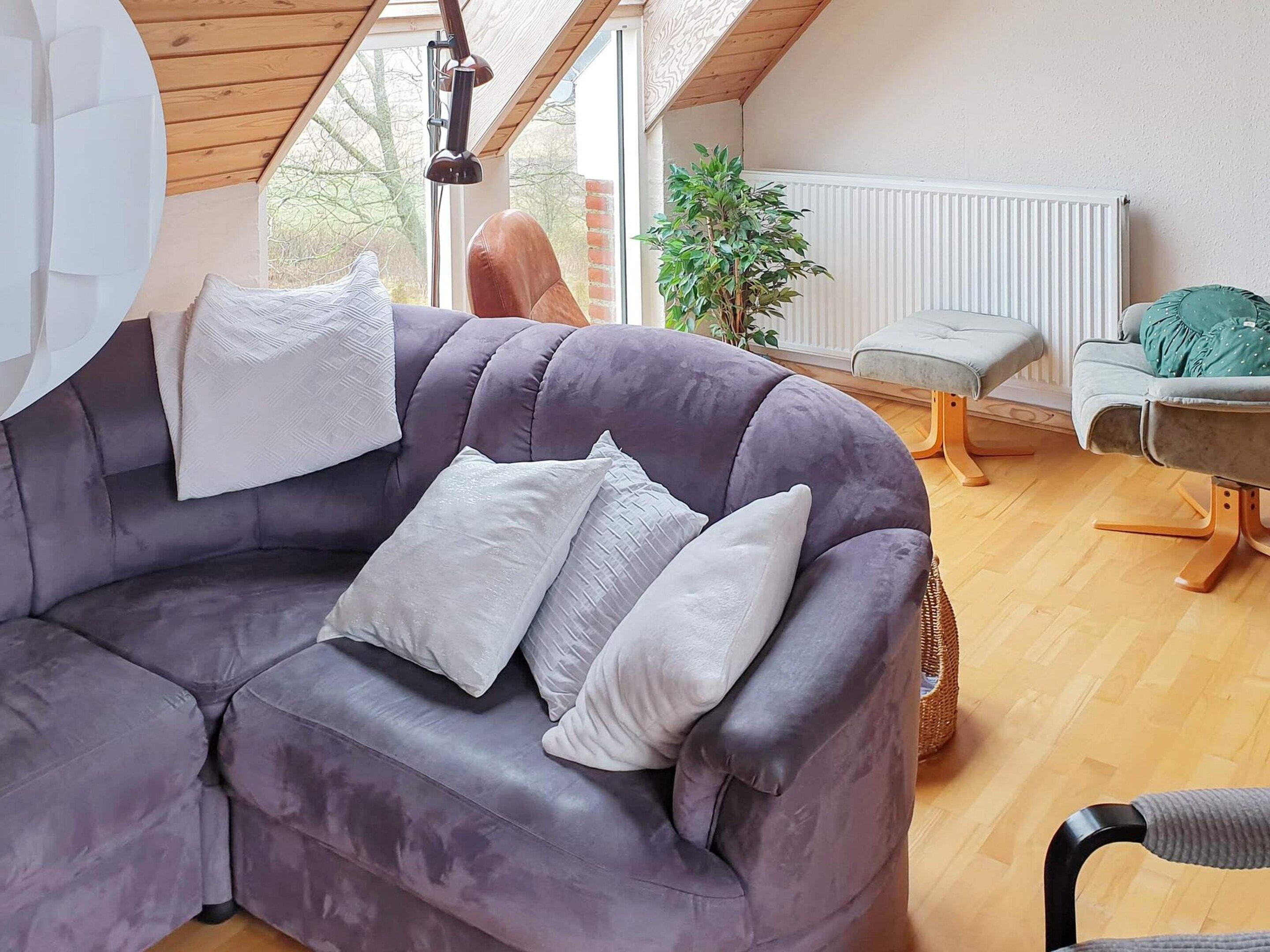 A modern living room with a grey sectional sofa, a small round table, and a chair.