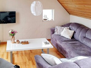 A modern living room with a white table, purple sofa, and a wooden ceiling. - 6 Person Holiday Home in Farso (Farso)