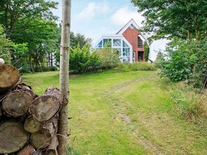 A modern house with a sloped roof, surrounded by a grassy yard and dense foliage. - 6 Person Holiday Home in Farso (Farso)