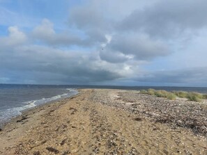 A pebbly beach with a view of the sea and overcast sky. - 6 Person Holiday Home in Farso (Farso)