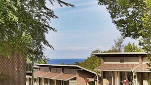 A building with a brick facade, a covered patio area, and a view of the ocean.