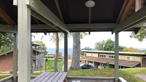 A covered outdoor area with picnic tables and a view of buildings and trees.