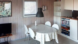 Une cuisine de taille réduite comprenant une table à manger, des chaises, un téléviseur et une bibliothèque.