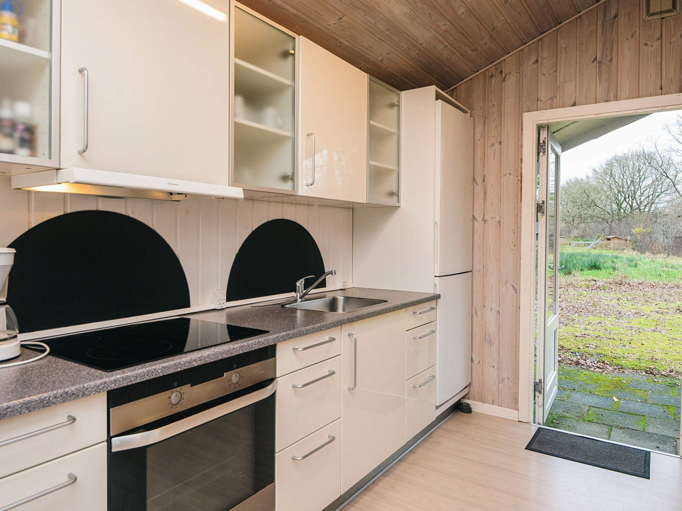 A modern kitchen with white cabinets, a black countertop, and a built-in oven.