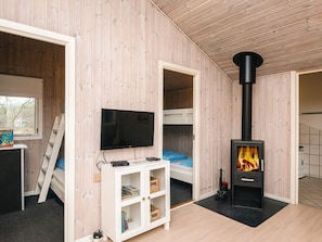 Quarto com televisão, beliches, armário branco e lareira a lenha.