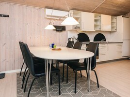 Cocina moderna con armarios blancos, una mesa de comedor redonda y sillas negras.