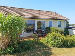 A house with a tiled roof, a deck, and a patio area with outdoor furniture.