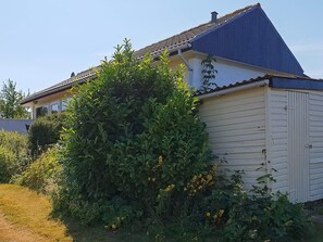 A house with a sloped roof, a garage, and dense greenery in front.