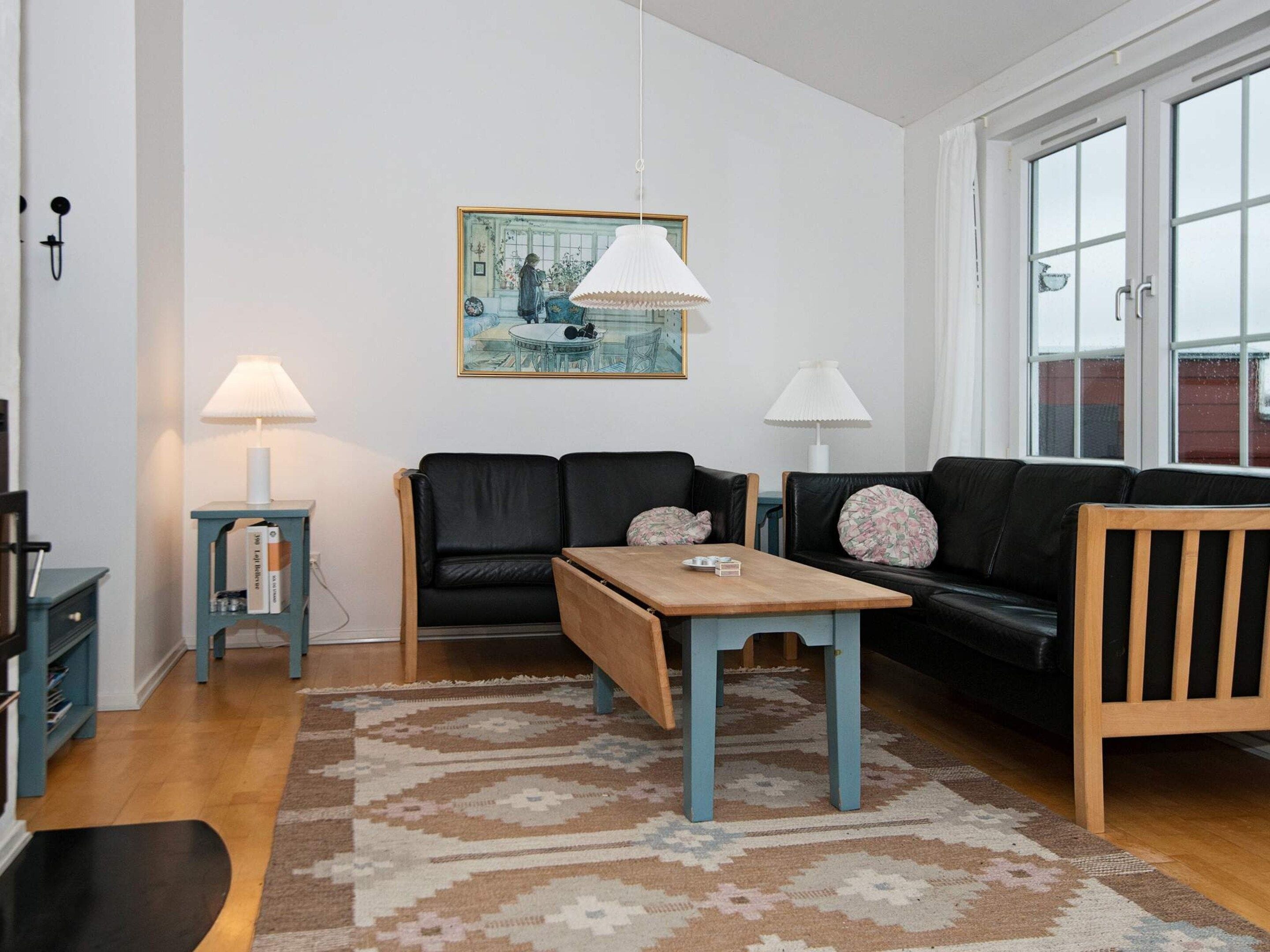 A living room with a sofa, a wooden table, a patterned rug, and a painting on the wall.