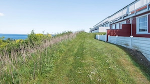 A row of red and white cabins with a grassy path leading to the beach. - 6 Person Holiday Home in Aabenraa (Aabenraa)