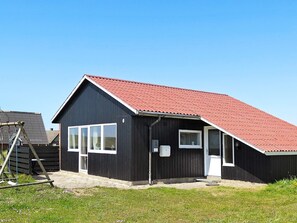 A black building with a red roof, white windows, and a door. - 8 Person Holiday Home in Harboore (Harboore)