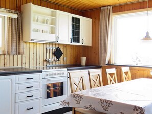 A kitchen with wooden cabinets, a stove, and a dining area with a table set for two.