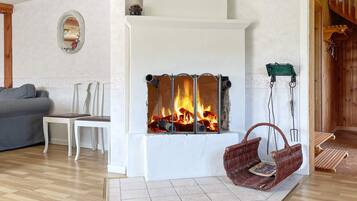 A living room with a fireplace, a grey sofa, a white chair, and a wicker swing chair.