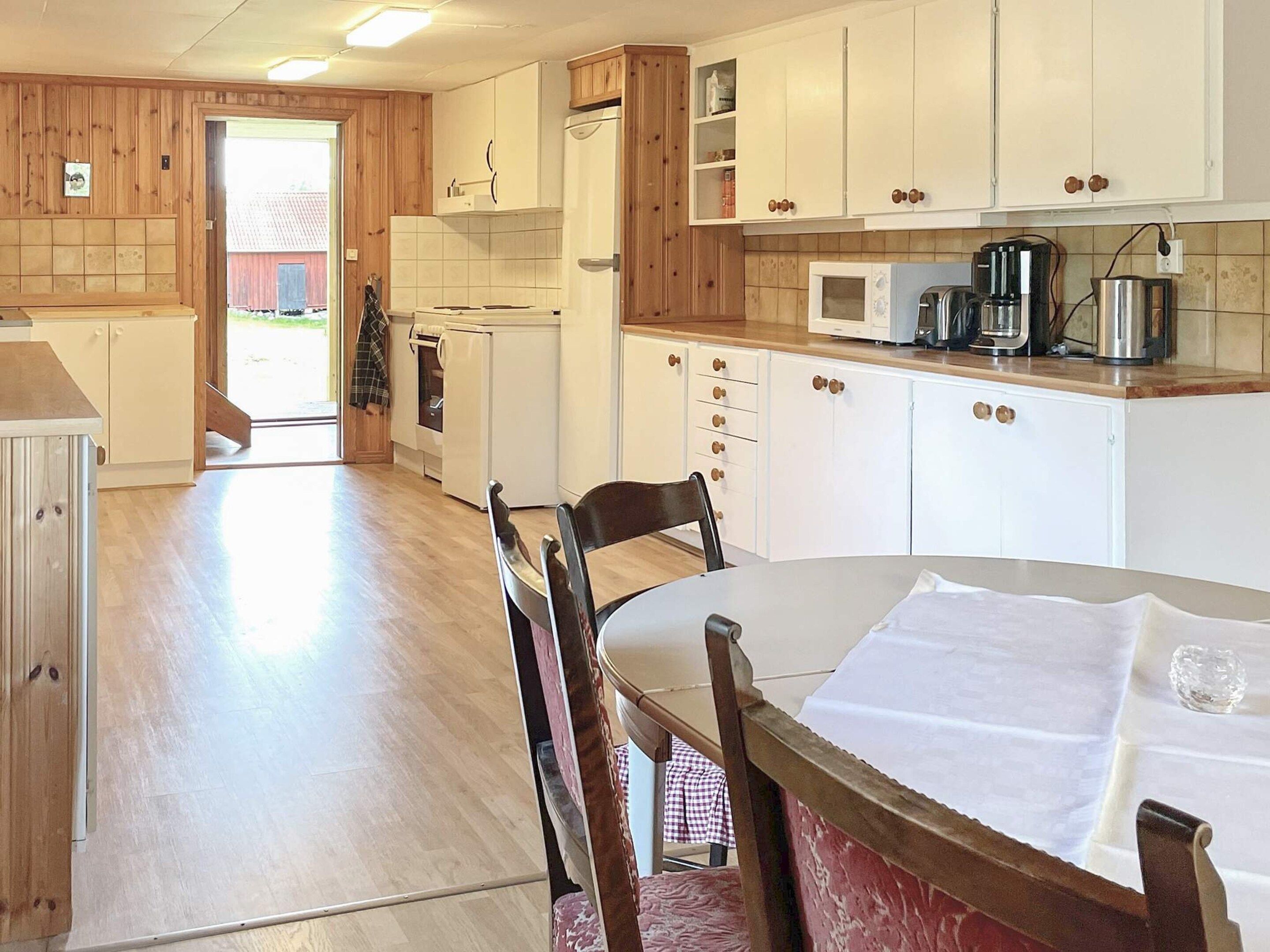 A kitchen with wooden cabinets, a microwave, and a dining table with chairs.