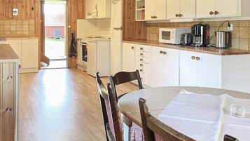 A kitchen with wooden cabinets, a microwave, and a dining table with chairs.