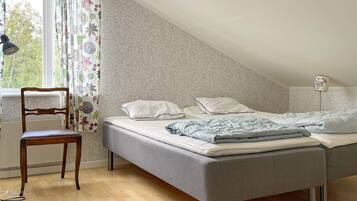A bedroom with a bed, a chair, a window with curtains, and a lamp.