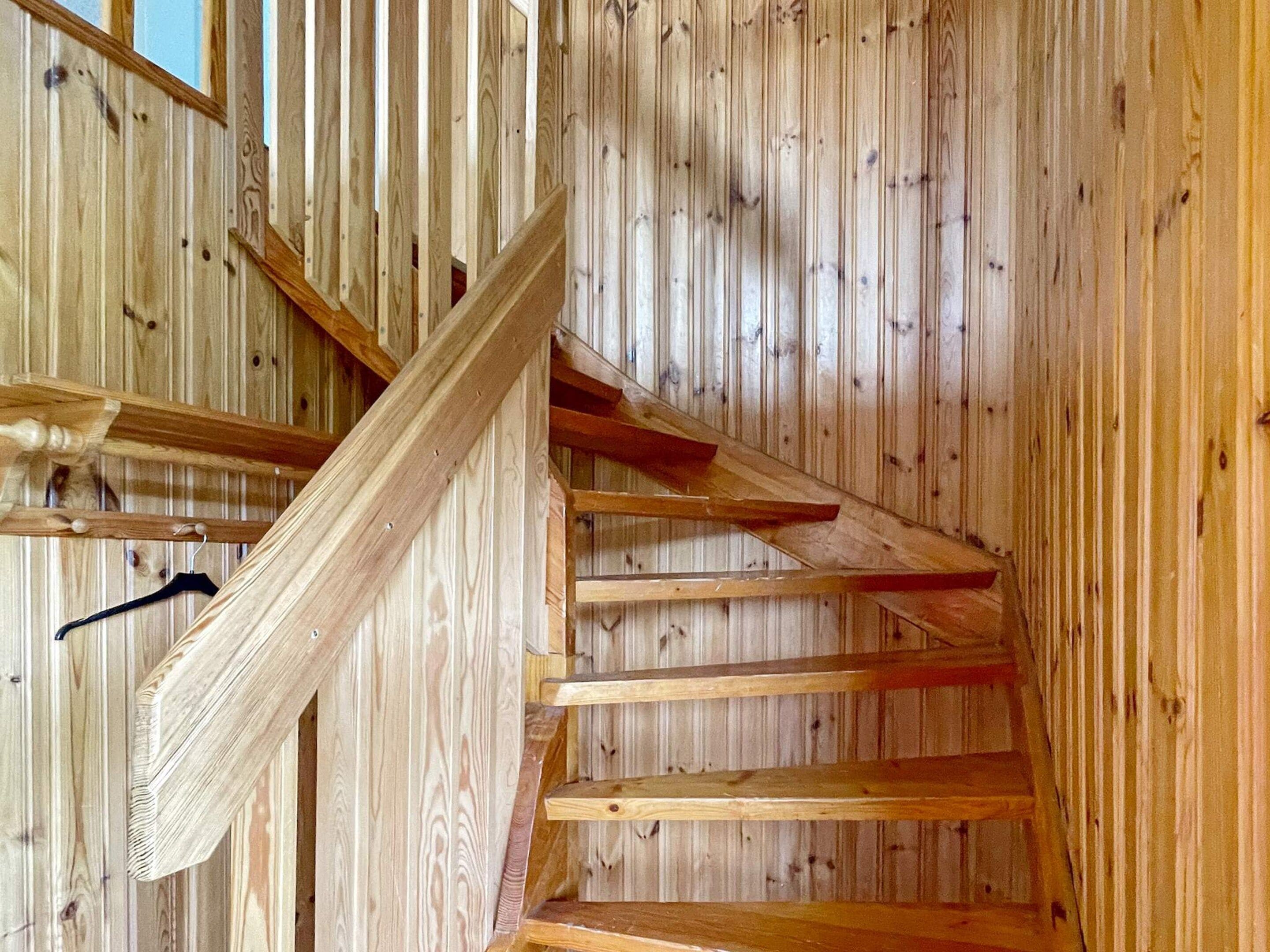 Un escalier en bois avec une rampe et un porte-manteau noir.