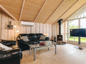 Ein gemütliches Wohnzimmer mit einem Ledersofa, einem Glastisch und einem großen Fenster.