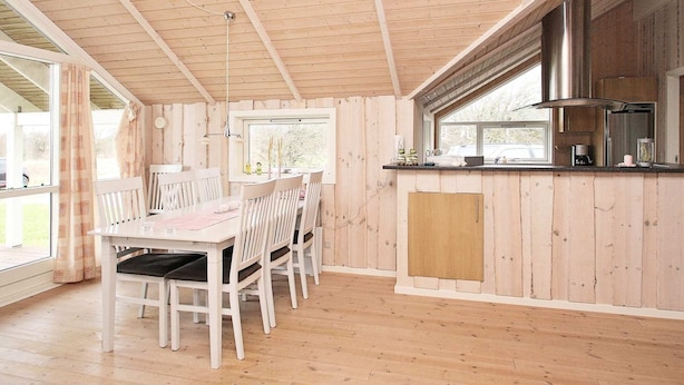 Un interior de madera con comedor, cocina y ventanas amplias.