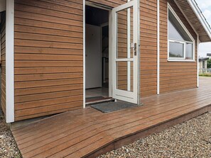 A wooden building with a door open, revealing an interior space.