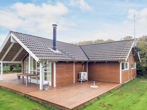 A modern house with a sloped roof, a chimney, and a wooden deck.
