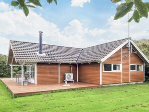 A wooden house with a tiled roof, a chimney, and a deck.