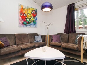 A living room with a brown sofa set, a white coffee table, a colorful abstract painting, a purple pendant light, and a floor lamp. - Idyllic Holiday Home in Store Fuglede near Forest (Store Fuglede)