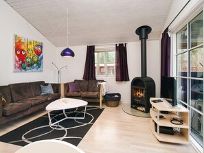 A living room with a sofa, a coffee table, a fireplace, and a large window. - Idyllic Holiday Home in Store Fuglede near Forest (Store Fuglede)