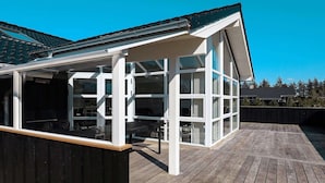 A covered outdoor area with a wooden deck and glass walls.