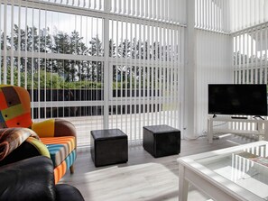 A modern living room with a large window, a flat-screen TV, a sofa, and a coffee table. - 5 Star Holiday Home in Lokken (Lokken)