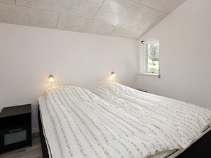 A single bed with a floral-patterned bedspread in a room with white walls and a sloped ceiling.