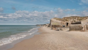 A beach with large concrete structures, a sandy shore, and the ocean.