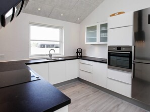 A modern kitchen with white cabinets, a stainless steel refrigerator, and a built-in oven.